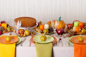 Thanksgiving dinner. Seasonal table setting with autumn leaves, candles and pumpkins.