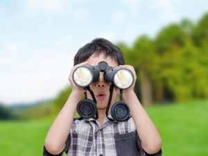 boy using binoculars at sleepaway camp