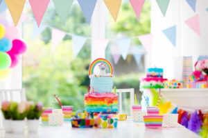 unicorn party supplies and cake with rainbow