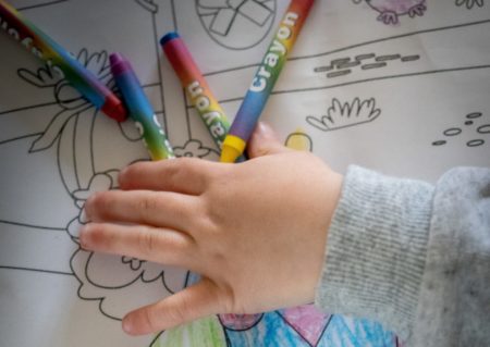 childs hand with crayons and coloring social distance activity
