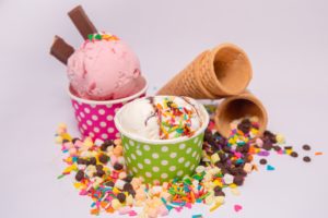 cups of ice cream and cones with toppings around