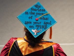 person wearing decorated graduation cap with text